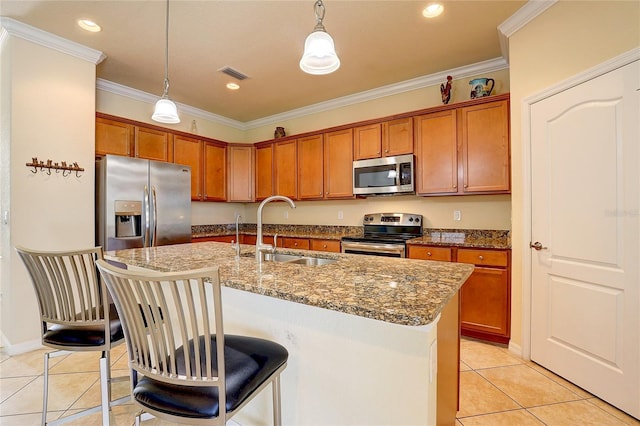 kitchen with sink, light tile patterned floors, appliances with stainless steel finishes, a kitchen island with sink, and hanging light fixtures