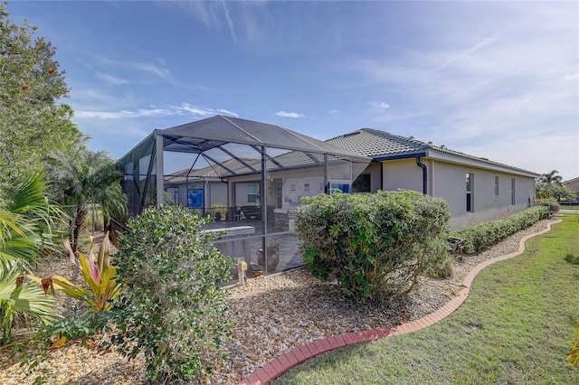 back of house featuring a lanai and a yard