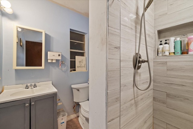 bathroom with vanity, toilet, and a tile shower