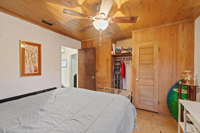 bedroom with ceiling fan, light parquet flooring, wood walls, and wood ceiling