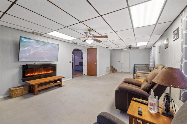 living room with ceiling fan, a paneled ceiling, and a fireplace