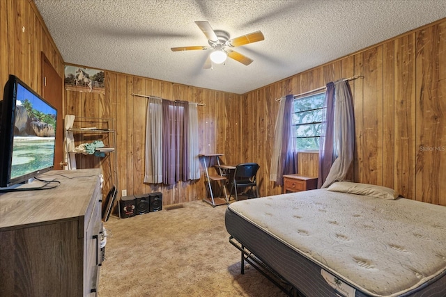 bedroom featuring light carpet, wooden walls, a textured ceiling, and ceiling fan