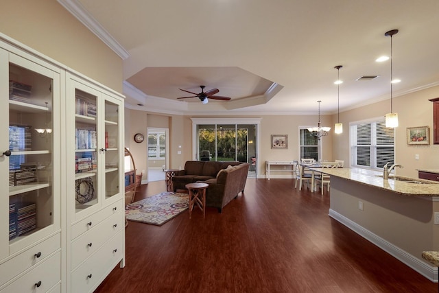 living room with sink, a raised ceiling, ornamental molding, dark hardwood / wood-style flooring, and ceiling fan with notable chandelier