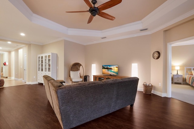 living room with crown molding, dark hardwood / wood-style flooring, ceiling fan, and a raised ceiling