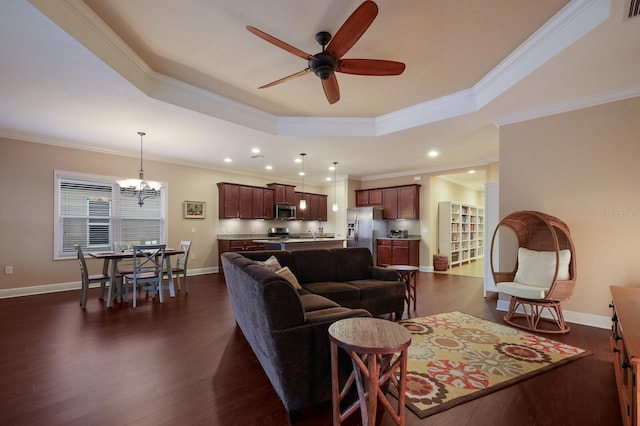 living room featuring ceiling fan with notable chandelier, crown molding, dark hardwood / wood-style flooring, and a tray ceiling