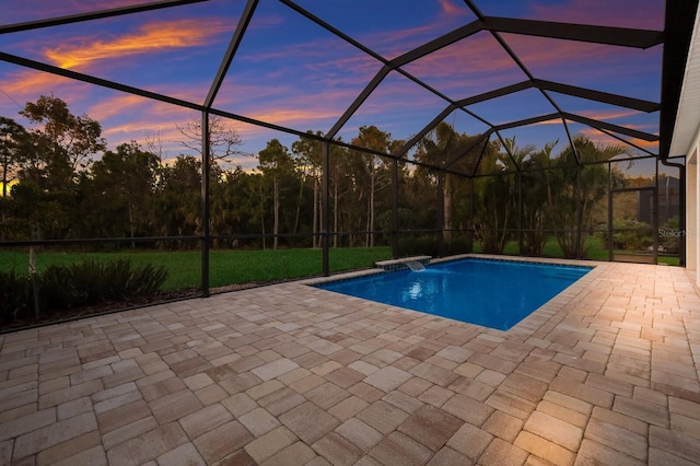 pool at dusk featuring glass enclosure and a patio