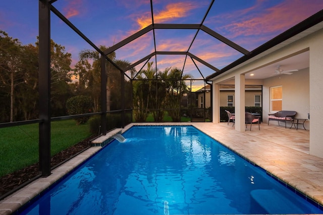 pool at dusk with glass enclosure, a patio area, pool water feature, and ceiling fan