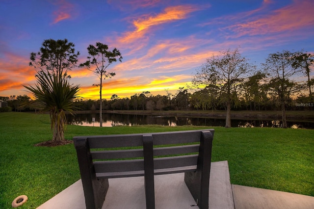 yard at dusk featuring a water view