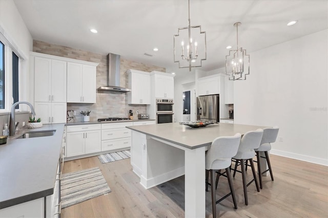 kitchen featuring white cabinetry, sink, stainless steel appliances, and wall chimney exhaust hood