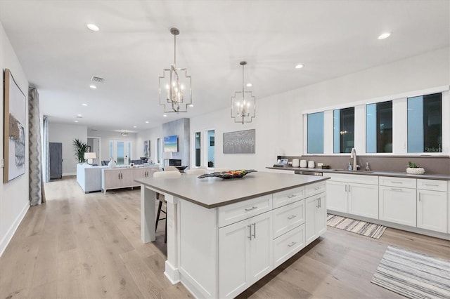 kitchen featuring white cabinetry, sink, a center island, and pendant lighting