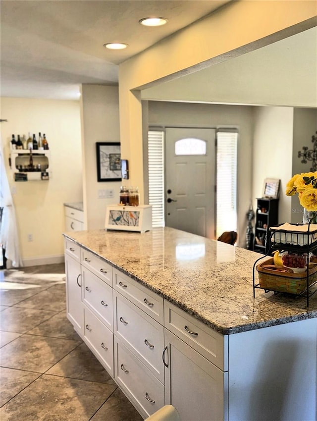 kitchen featuring light stone counters and white cabinets