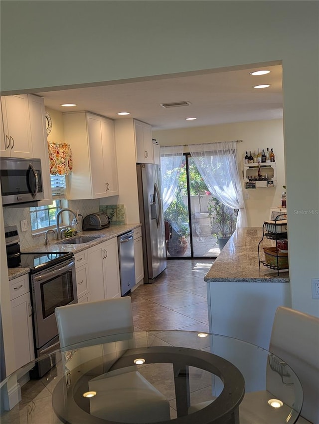 kitchen with appliances with stainless steel finishes, sink, white cabinets, and decorative backsplash