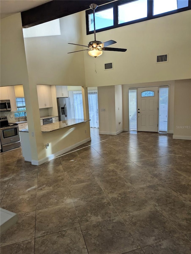 unfurnished living room with a towering ceiling and ceiling fan