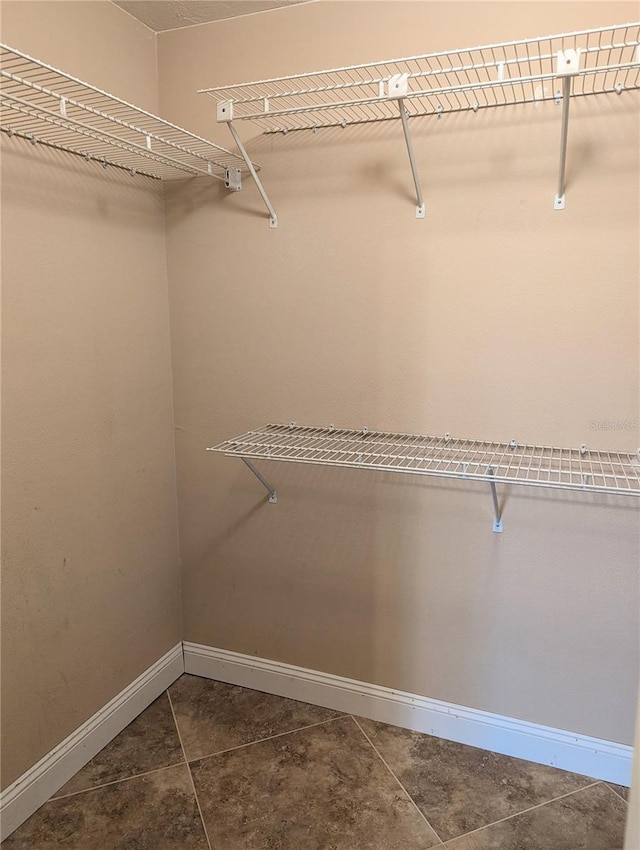 spacious closet featuring dark tile patterned floors