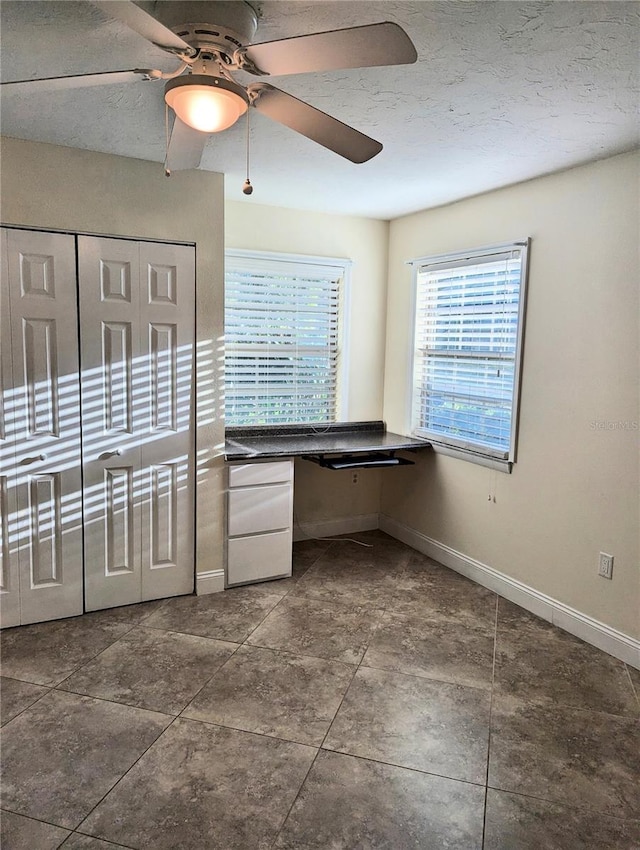 kitchen featuring ceiling fan, built in desk, and a textured ceiling