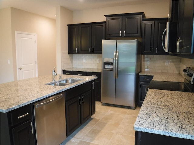 kitchen featuring sink, light tile patterned floors, stainless steel appliances, a center island with sink, and decorative backsplash