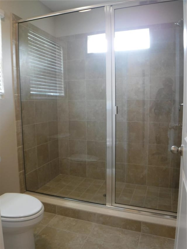 bathroom with walk in shower, tile patterned floors, and toilet