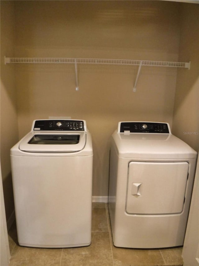 clothes washing area featuring washing machine and clothes dryer and light tile patterned floors