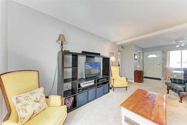 carpeted living room with ceiling fan and beamed ceiling