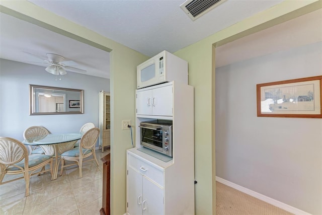 kitchen with white cabinetry and ceiling fan