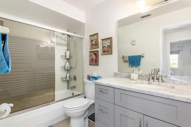 full bathroom with bath / shower combo with glass door, vanity, and toilet