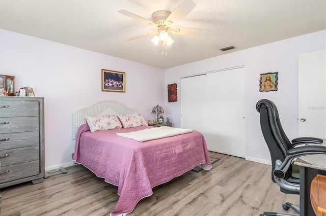 bedroom featuring a textured ceiling, light hardwood / wood-style flooring, a closet, and ceiling fan