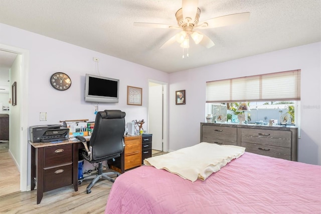 bedroom with ceiling fan, a textured ceiling, and light hardwood / wood-style floors