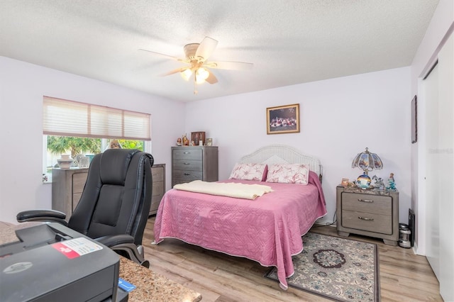 bedroom with ceiling fan, a closet, a textured ceiling, and light hardwood / wood-style flooring