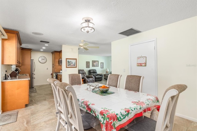 dining space featuring ceiling fan, sink, and a textured ceiling