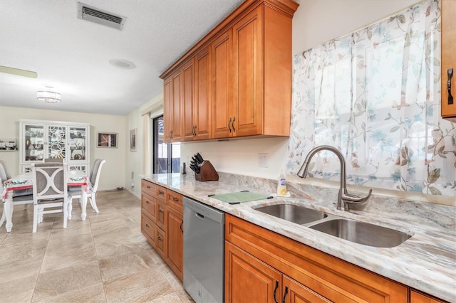 kitchen with stainless steel dishwasher, light stone countertops, sink, and a textured ceiling