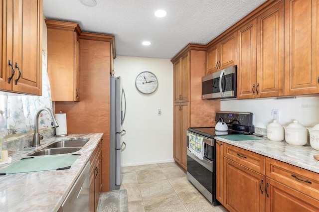 kitchen with light stone countertops, appliances with stainless steel finishes, sink, and a textured ceiling