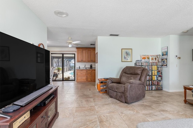 living room featuring ceiling fan and a textured ceiling