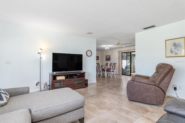 living room with ceiling fan and a textured ceiling