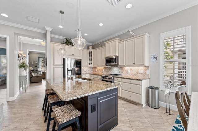 kitchen featuring pendant lighting, sink, a kitchen island with sink, stainless steel appliances, and light stone countertops