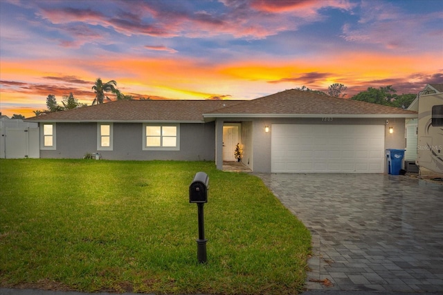 single story home featuring a garage and a yard