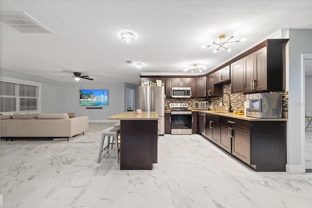 kitchen with sink, a breakfast bar area, tasteful backsplash, appliances with stainless steel finishes, and a kitchen island