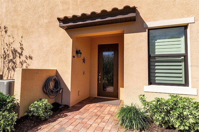 view of exterior entry with cooling unit and a patio area