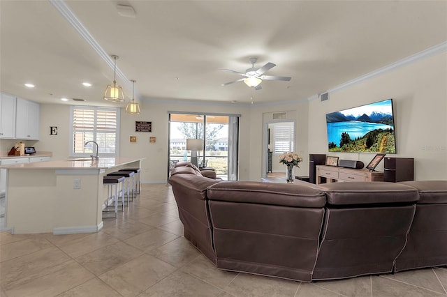 living room with sink, plenty of natural light, ornamental molding, and ceiling fan