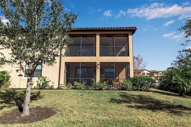 rear view of house with a lawn and a sunroom