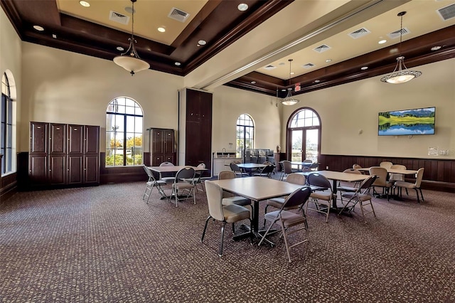 dining room featuring a raised ceiling, dark colored carpet, a towering ceiling, and a healthy amount of sunlight