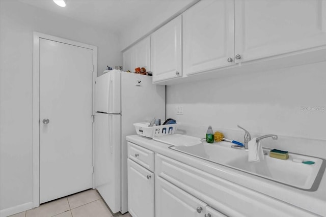 kitchen with sink, white cabinetry, white fridge, and light tile patterned flooring