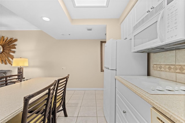 kitchen featuring backsplash, white appliances, light tile patterned floors, and white cabinets