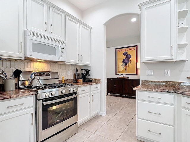 kitchen featuring stainless steel gas stove, light tile patterned floors, white cabinetry, and dark stone countertops