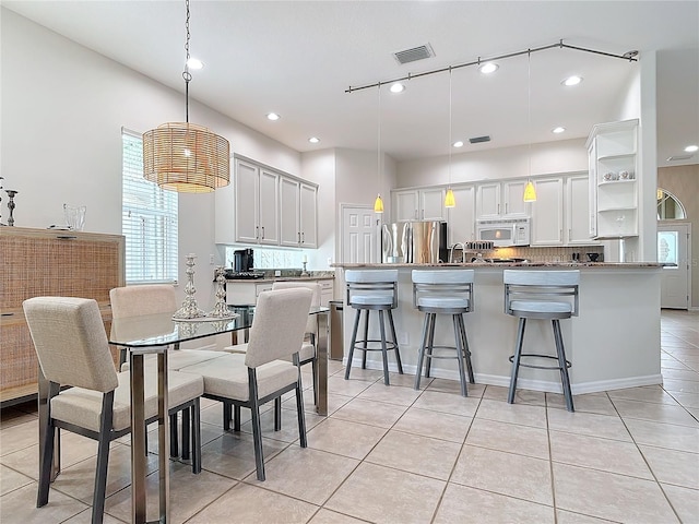 kitchen featuring hanging light fixtures, white cabinets, a kitchen bar, and stainless steel fridge with ice dispenser