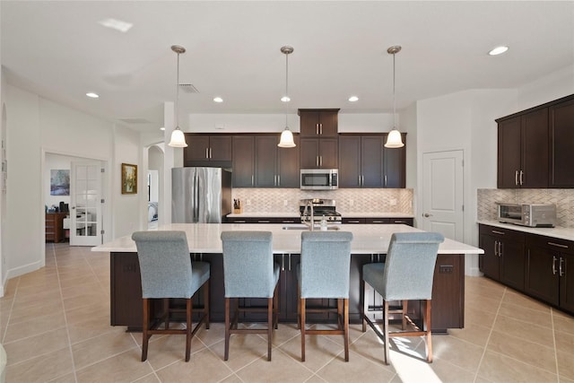 kitchen featuring hanging light fixtures, an island with sink, and appliances with stainless steel finishes