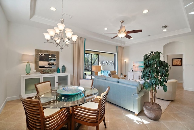 dining area with ornamental molding, ceiling fan with notable chandelier, light tile patterned floors, and a tray ceiling