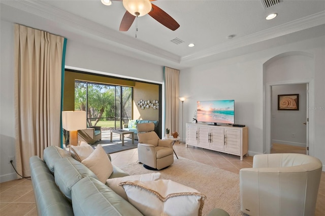 tiled living room featuring crown molding, ceiling fan, and a raised ceiling