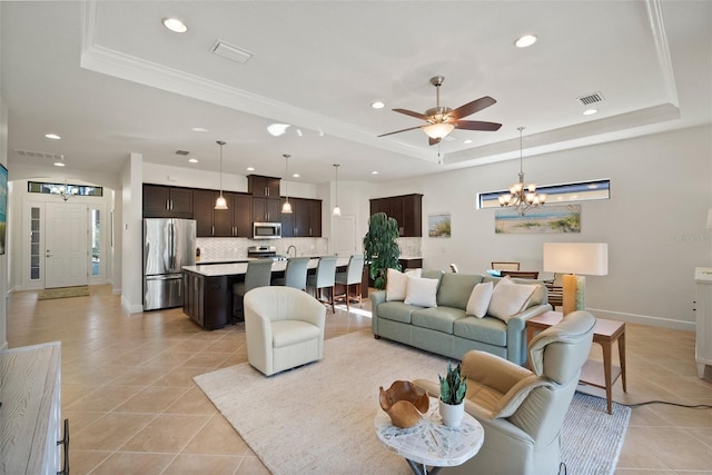 living room featuring light tile patterned floors, a tray ceiling, ceiling fan with notable chandelier, and ornamental molding