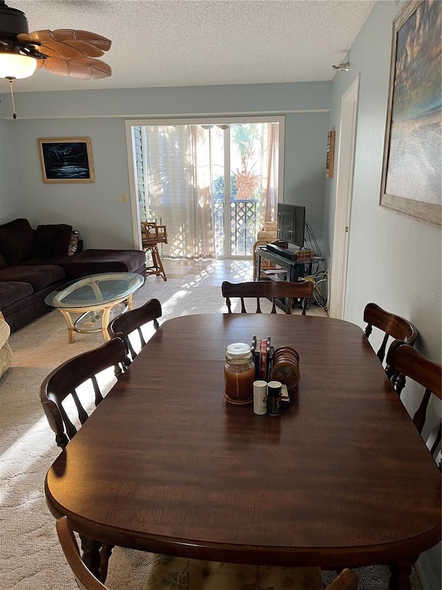 dining space with light carpet and a textured ceiling