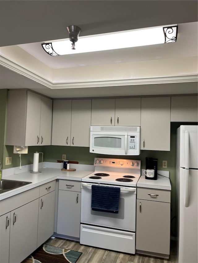 kitchen featuring white appliances, sink, hardwood / wood-style floors, and white cabinets